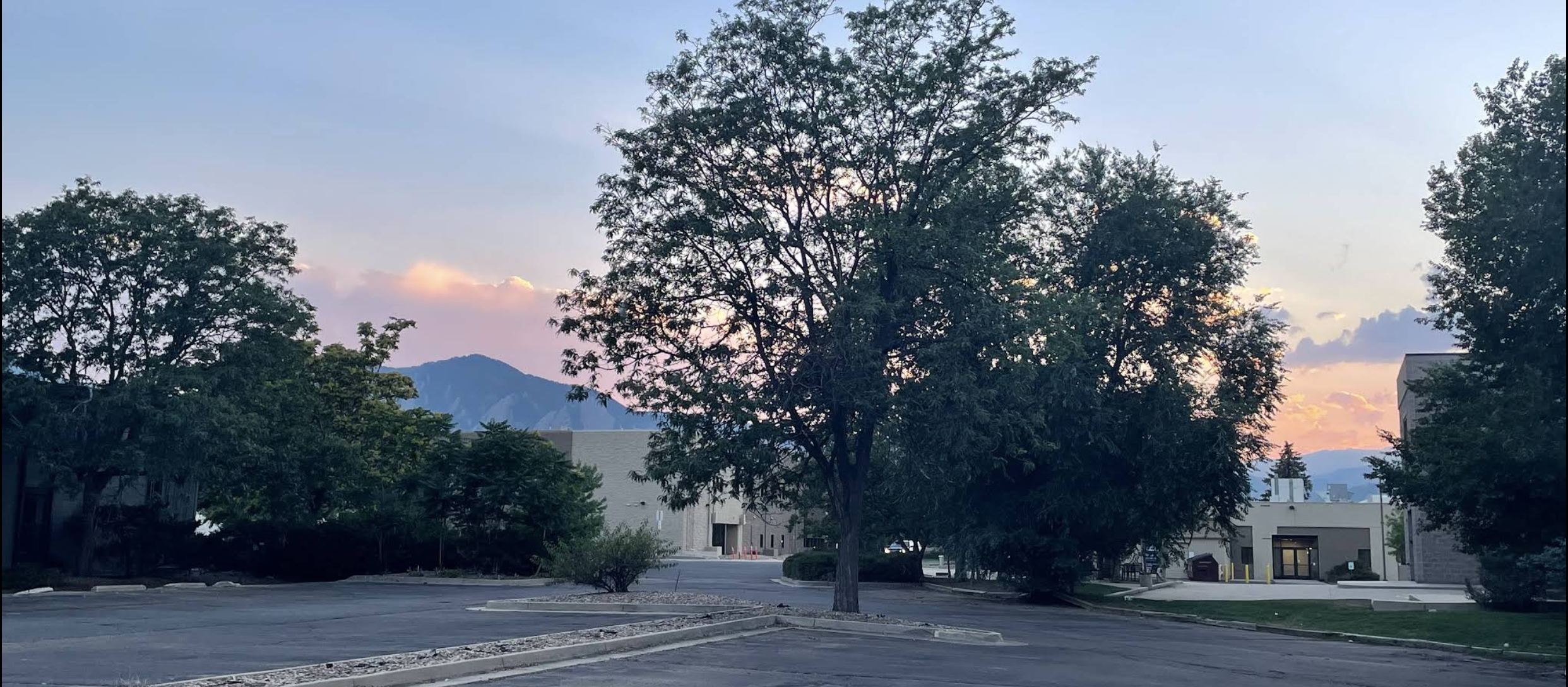 Exterior of Cognativ in Boulder, Colorado, with trees and mountains at sunset